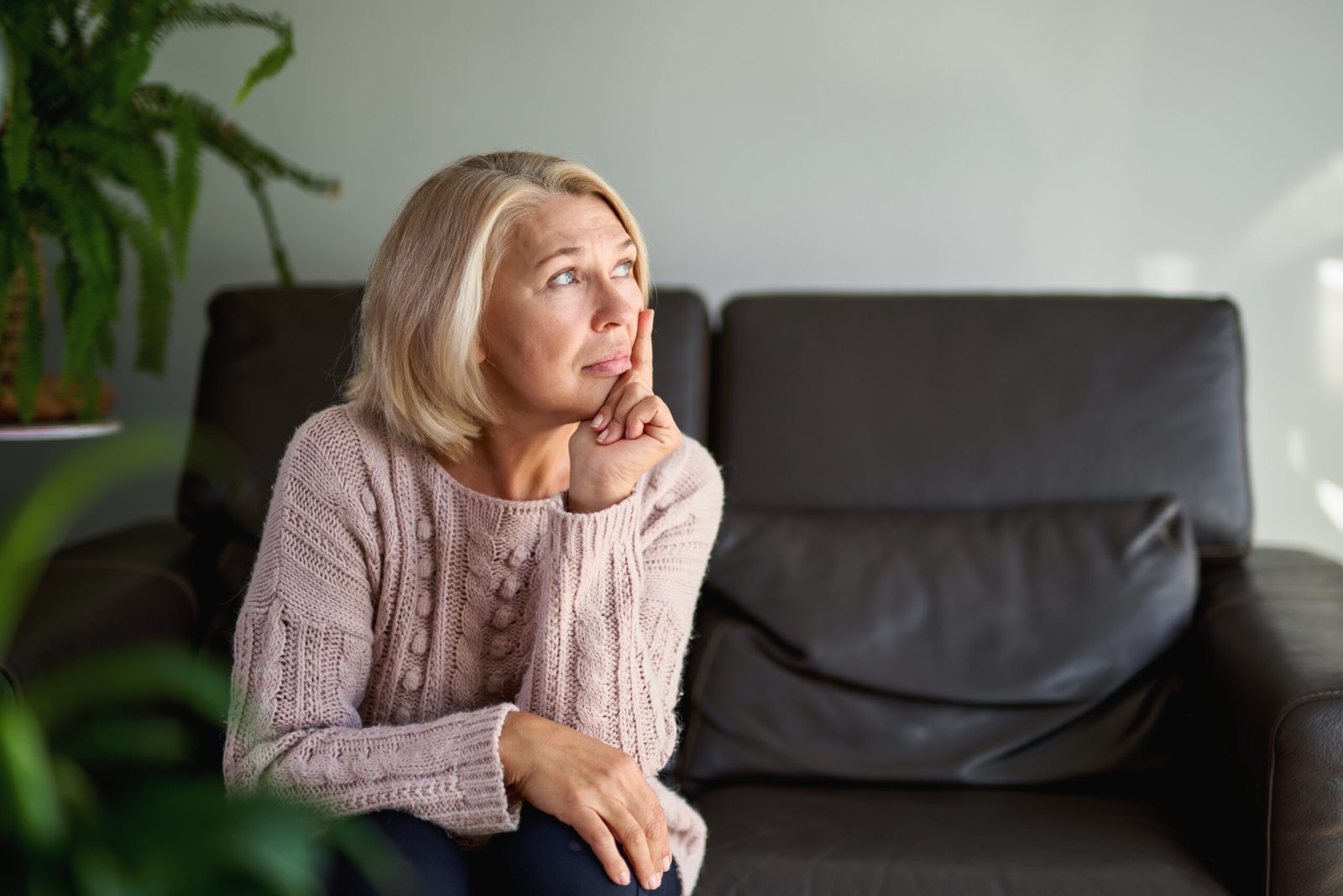 Person sitzt nachdenklich auf einem Sofa und sucht nach Ursachen für Knarzgeräusche